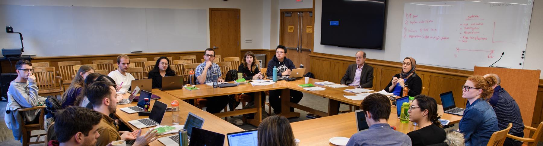 Graduate students and faculty seated around seminar table