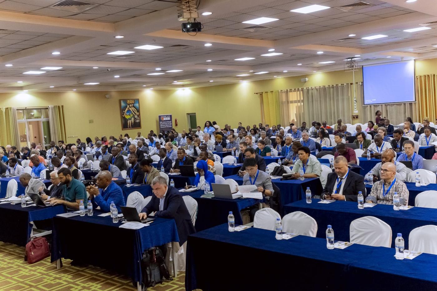 Conference of African Materials Research Society audience, sitting at tables in a large conference room listening to Professor Wantchekon speak