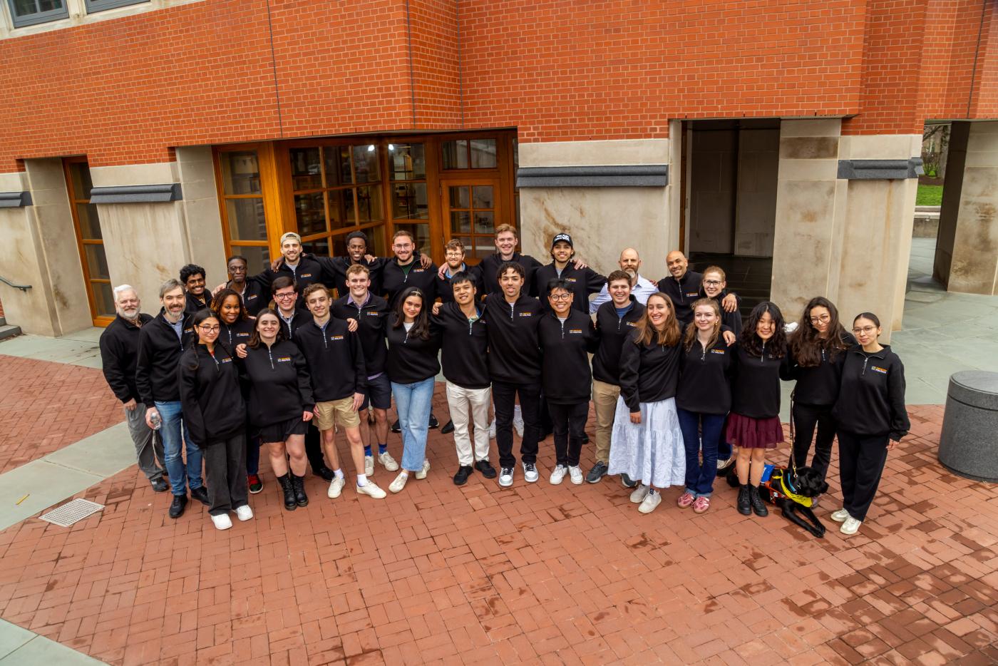 A crowed of students, faculty, and staff gather in their new Politics sweatshirts in front of Fisher hall to celebrate.