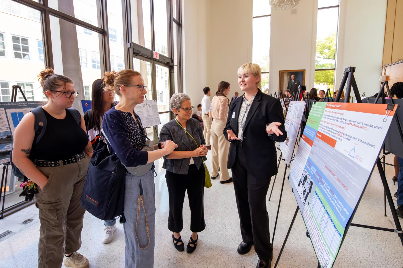 student discussing research poster to faculty