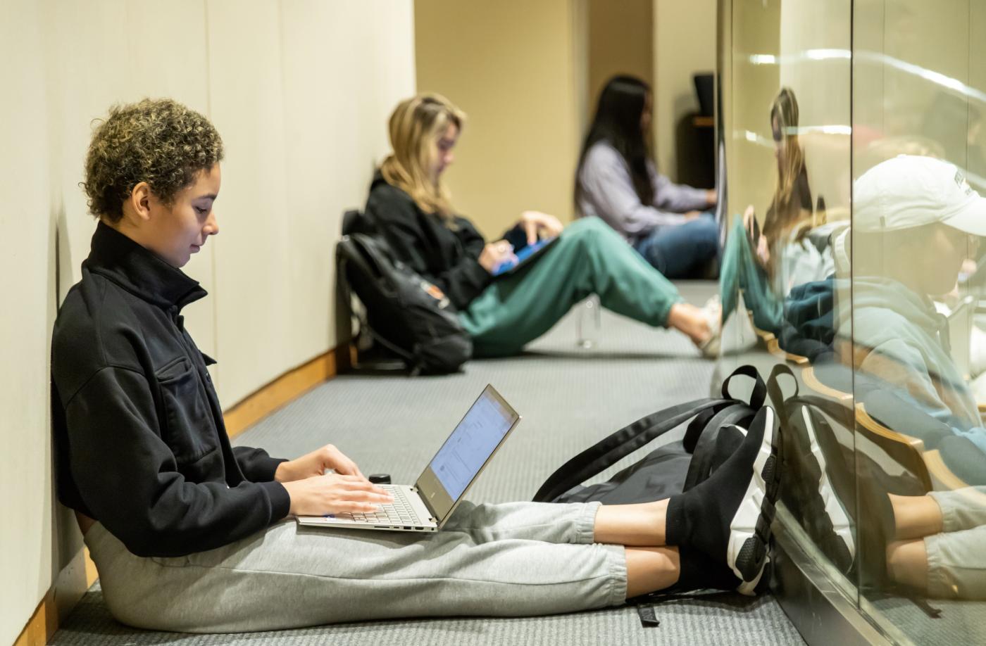 students sitting on the floor, working on laptops