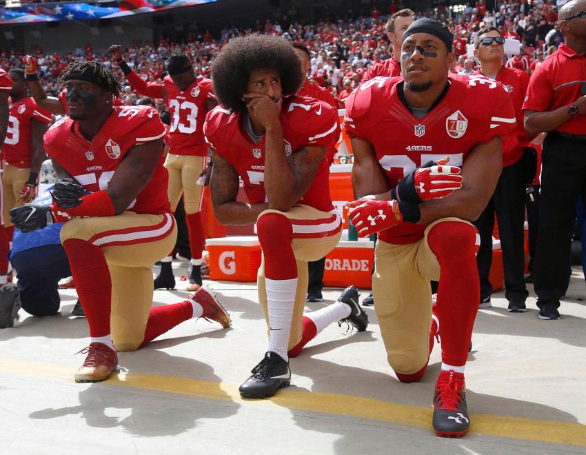 Colin Kaepernick and two other San Francisco 49er football players kneeling during the national anthem.
