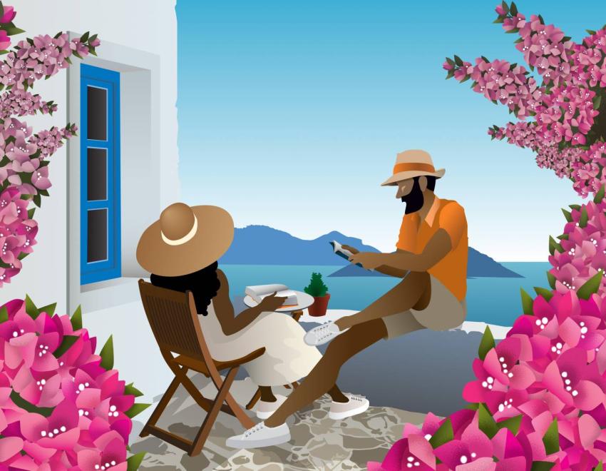 A couple read on a balcony in Greece overlooking the water surrounded by pink bougainvillea flowers.