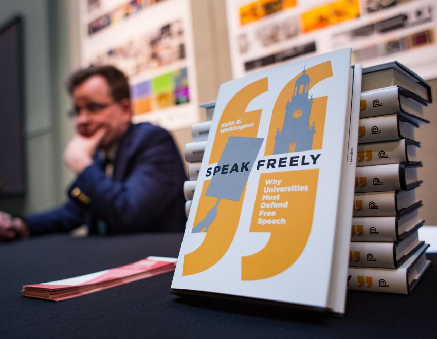 Professor Whitting at a table with his book "Speak Freely"
